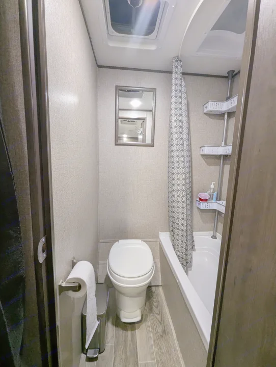RV rental's compact bathroom features a toilet, shower with curtain & caddy, mirror, and roof vent.. Jayco Jay Flight SLX 2021