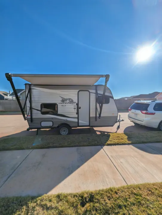 An RV rental, a Jayco travel trailer, is parked on a sunny day with its awning extended, perfect for camping.. Jayco Jay Flight SLX 2021