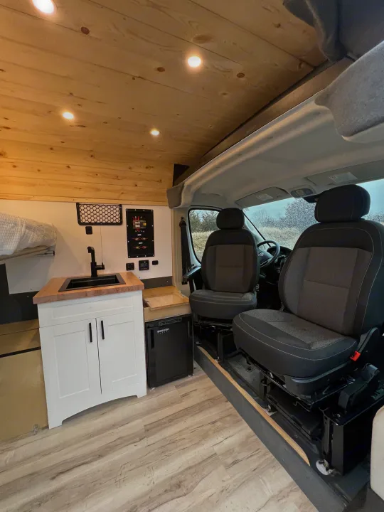 Clean RV rental interior with wood ceilings, a mini-kitchen, and front seats. Ready for your next adventure.. Ram Promaster 1500 2020