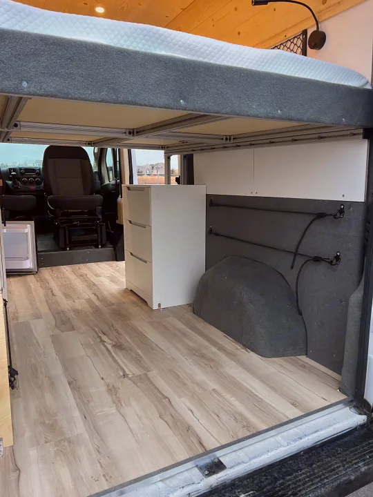 This RV rental offers a well-designed camper van interior with an elevated bed, ample storage, and light wood flooring.. Ram Promaster 1500 2020
