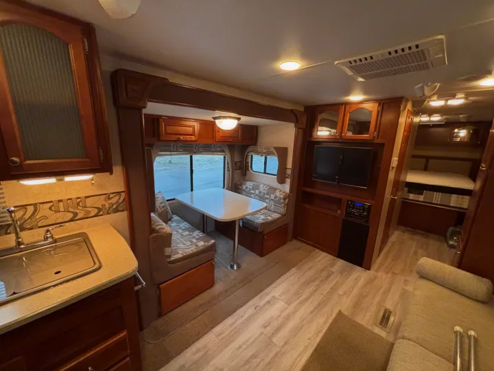 Explore this RV rental's full interior, featuring a dining booth, kitchen area, living space, and hallway to bunks.. Fleetwood 230RKS 2009