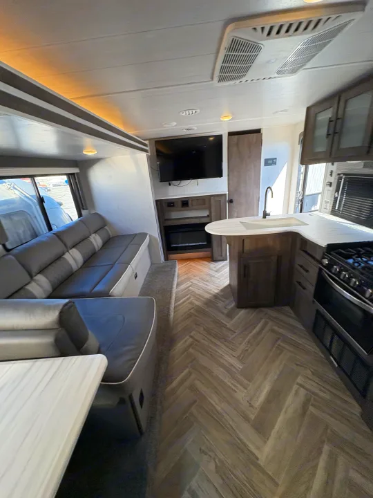 Spacious rv rental interior: modern kitchen, comfortable sofa, entertainment center with TV & fireplace.. Forest River Wildwood X-Lite 2022
