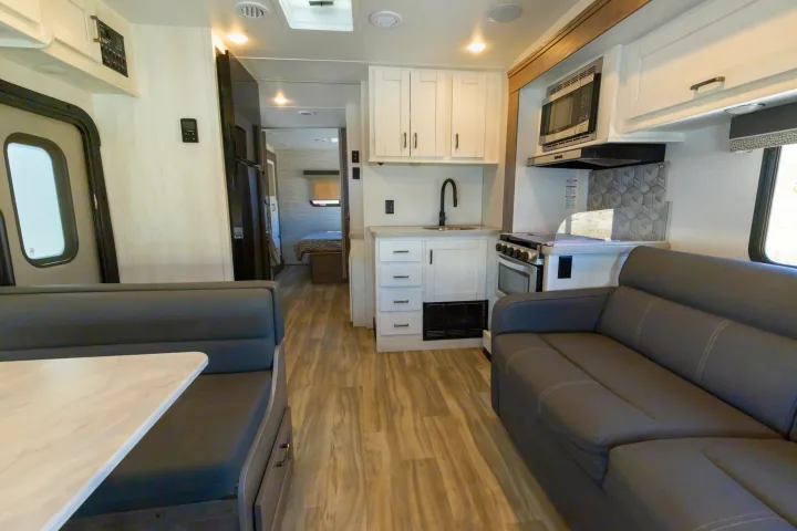 Clean RV rental interior: living area with dinette and sofa, full kitchen, and hallway leading to bedroom.. Gulf Stream Conquest 2024