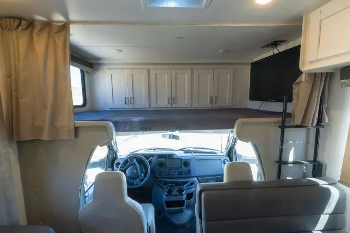 Inside this RV rental, see the spacious overhead bunk, driver's cockpit, ample storage cabinets, and TV setup.. Gulf Stream Conquest 2024