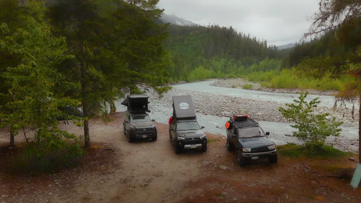 Overlanding trip: Three SUVs (two with rooftop tents) by a mountain river, offering an RV rental adventure experience.. Toyota 4Runner 2025