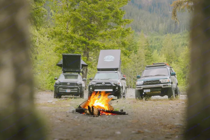 Three Toyota 4Runner SUVs with open rooftop tents and a campfire, perfect for your next RV rental overlanding trip.. Toyota 4Runner 2025