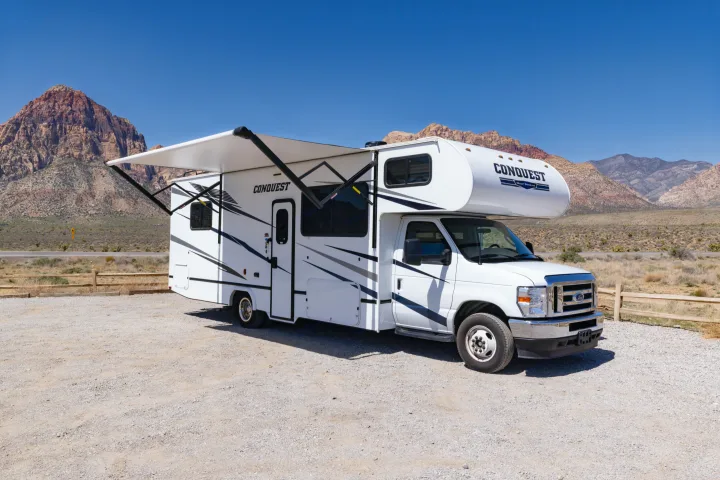 White Gulf Stream Conquest RV rental parked in a sunny desert. Red mountains and clear blue sky frame the scene.. Gulf Stream Conquest 2024