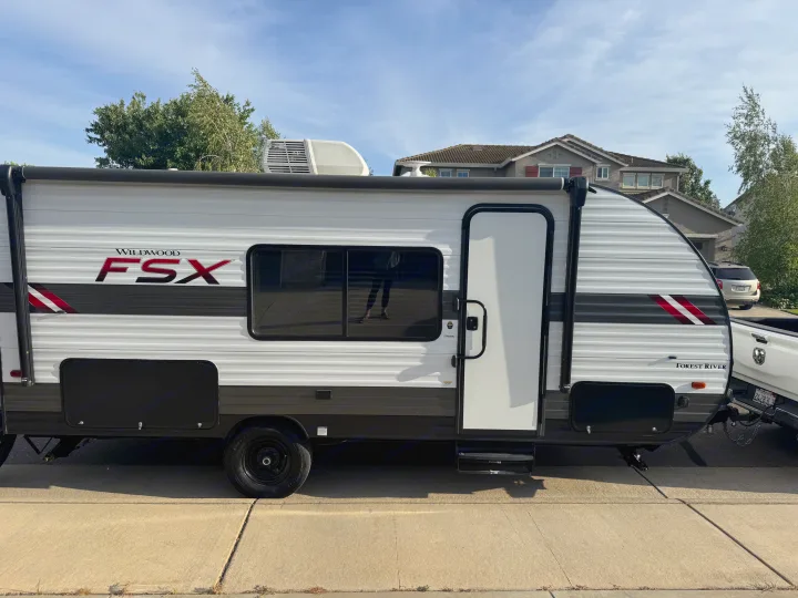 A bright white and gray Forest River Wildwood FSX travel trailer. This RV rental is ready for your next getaway!. Forest River Wildwood FSX 2021