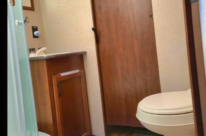RV rental bathroom features a toilet, sink vanity with cabinet, and shower door. Wood and light tones define the compact space.. Jayco Jay Flight SLX 2016