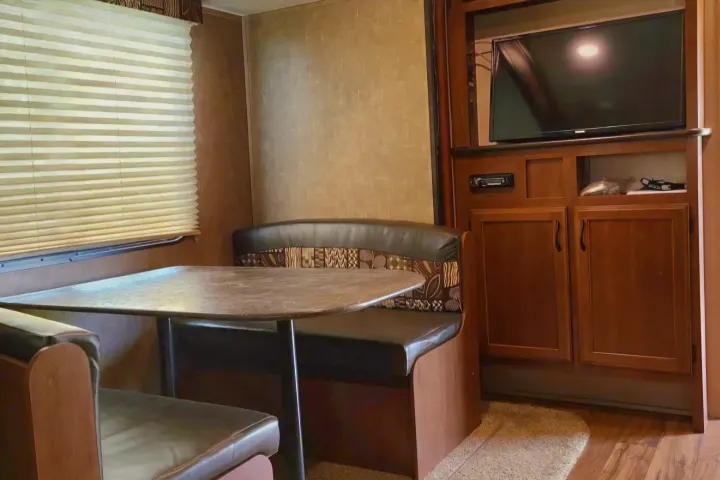 RV rental: Dinette with table & benches, TV, and storage cabinets inside a well-appointed travel trailer.. Jayco Jay Flight SLX 2016