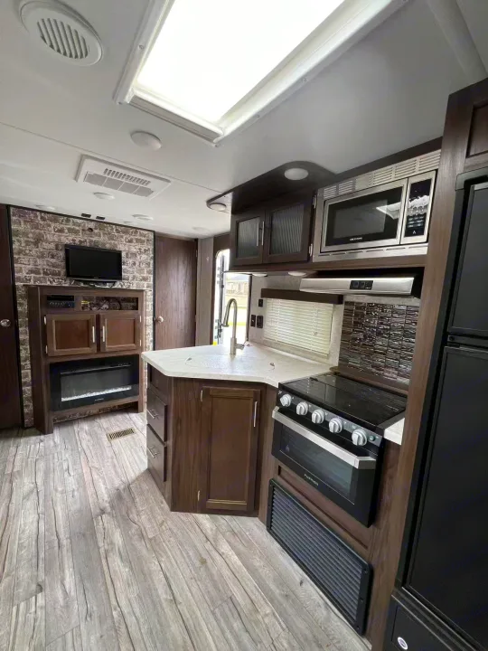 Spacious RV rental interior featuring a modern kitchen with appliances, an entertainment center with TV/fireplace, and cozy living space.. Forest River Cherokee 2018