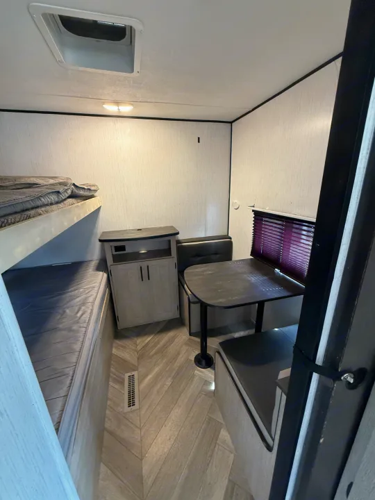 Compact rv rental interior with bunk beds, a dinette with table, and storage, maximizing space for comfortable travel.. Heartland RVs Prowler 2021
