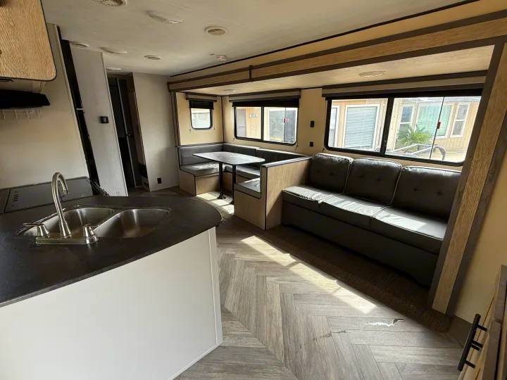 Spacious RV rental interior with a functional kitchen, U-shaped dinette, and comfy sofa, illuminated by natural light.. Heartland RVs Prowler 2021