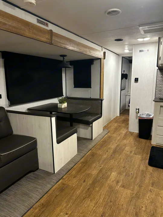 Spacious RV rental interior: dinette booth, modern wood-look flooring, and comfortable seating. Smoking prohibited.. 5sfeb3729me459252 31DB 2021