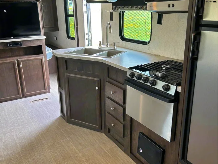 Spacious RV rental interior: kitchen with sink & stove, living area with TV, modern wood cabinets & flooring.. Starcraft Avalon 2018