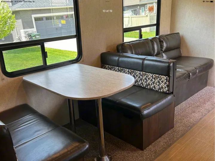 Spacious RV rental interior featuring a dinette with dark leather seating, a light table, and an extended lounge couch.. Starcraft Avalon 2018