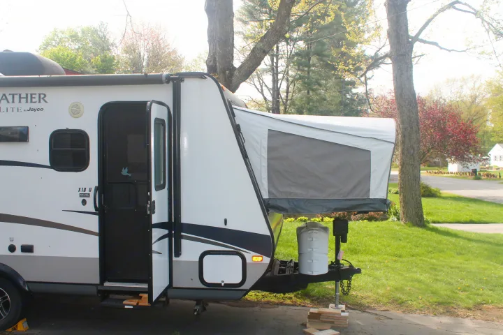 A white Jayco hybrid travel trailer, perfect as an RV rental, with its front tent-like section deployed.. Jayco Jay Feather Ultra Lite 2015
