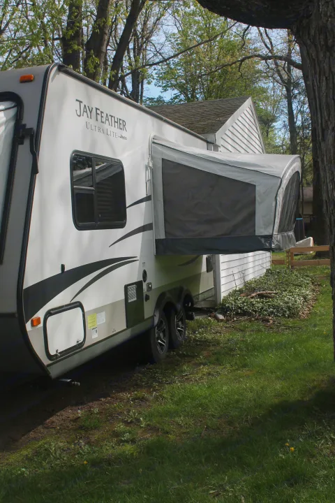 Experience outdoor adventures with this Jayco Jay Feather RV rental, featuring a pop-out extension for extra space next to a house.. Jayco Jay Feather Ultra Lite 2015