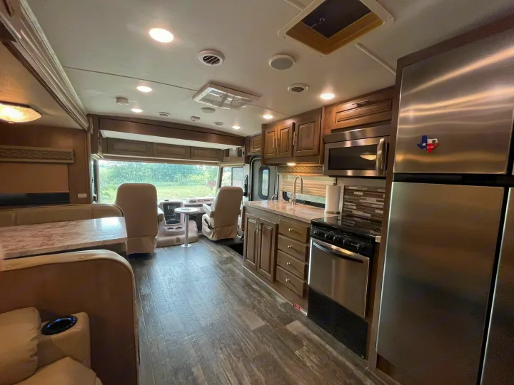 Spacious RV rental interior featuring a modern kitchen, dining booth, and front captain's chairs for comfortable travel.. Georgetown GT5 2019