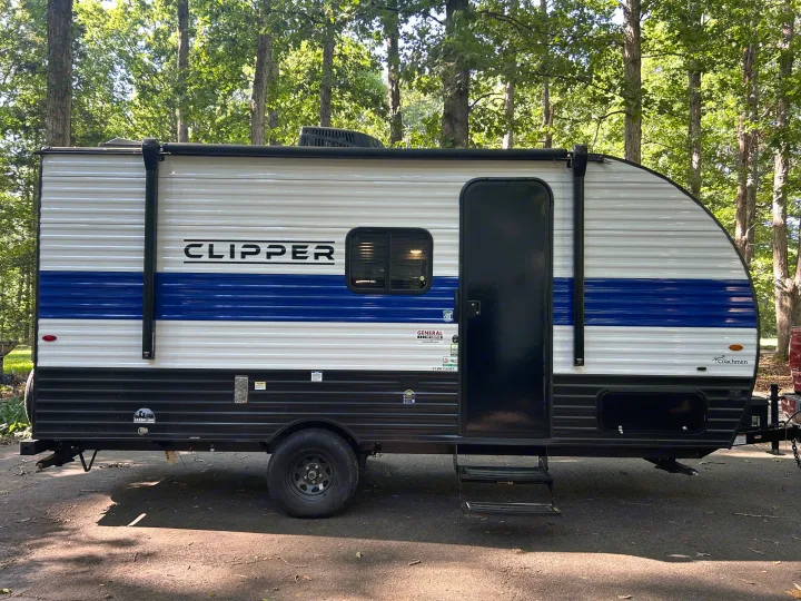 This white & blue Coachmen Clipper travel trailer is ready for an RV rental adventure in nature.. Clipper 17CBHCADET 2024