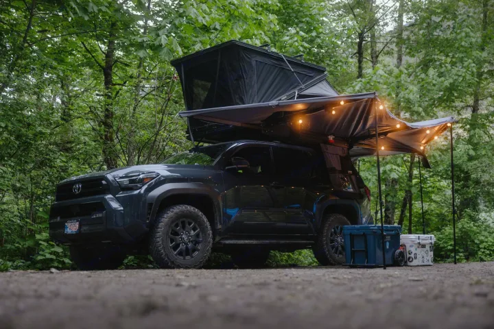 Explore nature with this overland RV rental setup! A dark SUV with rooftop tent, awning & lights, ready for adventure.. Toyota 4Runner 2025