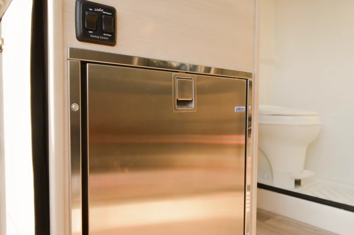 Explore this RV rental's interior: a sleek stainless steel fridge, power awning controls, and a glimpse of the compact bathroom.. Cahaba Cahaba Class B 2021