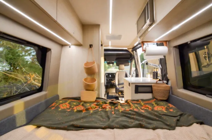 Inside an RV rental: a comfortable bed, functional kitchen, and scenic outdoor views through large windows.. Cahaba Cahaba Class B 2021
