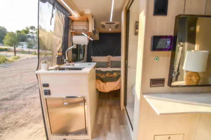 Experience comfort in this RV rental! Its camper van interior features a modern kitchen, cozy bed, and outdoor view.. Cahaba Cahaba Class B 2021