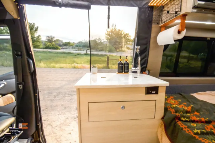 RV rental interior: cozy camper van with a compact kitchen, sink, and an outdoor view. Perfect for a road trip adventure!. Cahaba Cahaba Class B 2021