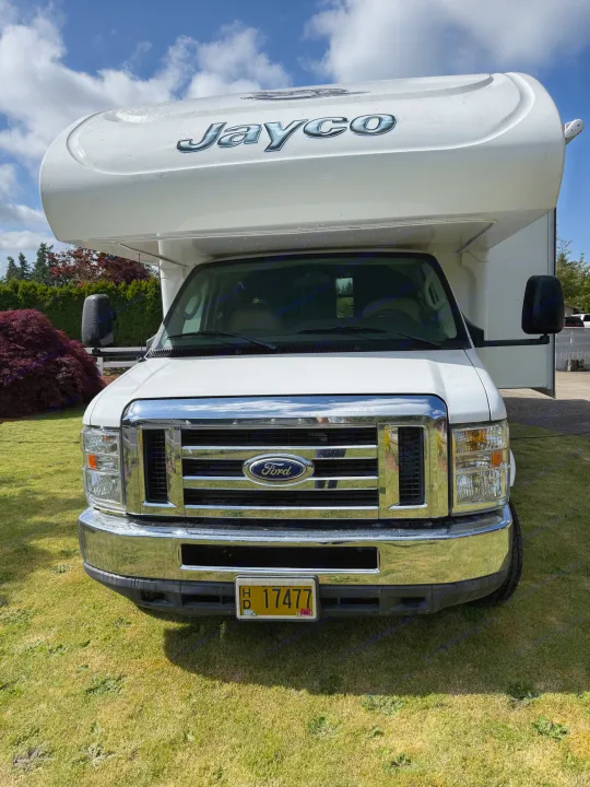 Front view of a white Ford Jayco Class C RV rental parked on a lawn. Ideal for your next adventure.. Jayco Greyhawk 2015