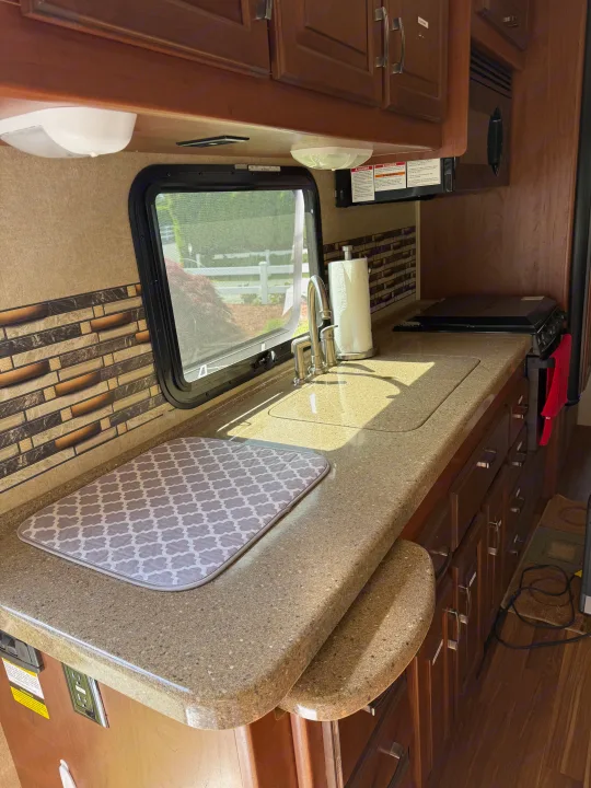 RV rental kitchen: Features a modern sink, microwave, stovetop, and ample counter space, perfect for travel meals.. Jayco Greyhawk 2015