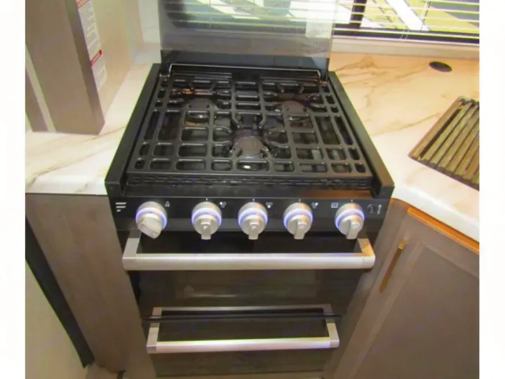Modern gas range with oven in an RV rental kitchen. Features illuminated knobs and a sleek countertop.. Thor Chateau 2024