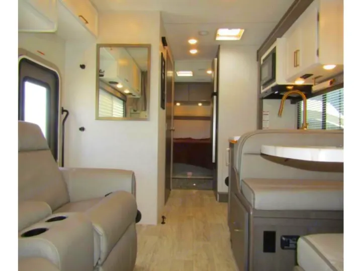 View inside a modern **RV rental** featuring a cozy living area, well-equipped kitchen, dining space, and rear bedroom.. Thor Chateau 2024