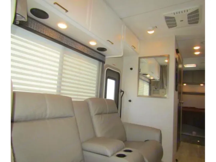 Comfortable RV rental interior with recliners, bright overhead lighting, window blinds, and ample storage.. Thor Chateau 2024