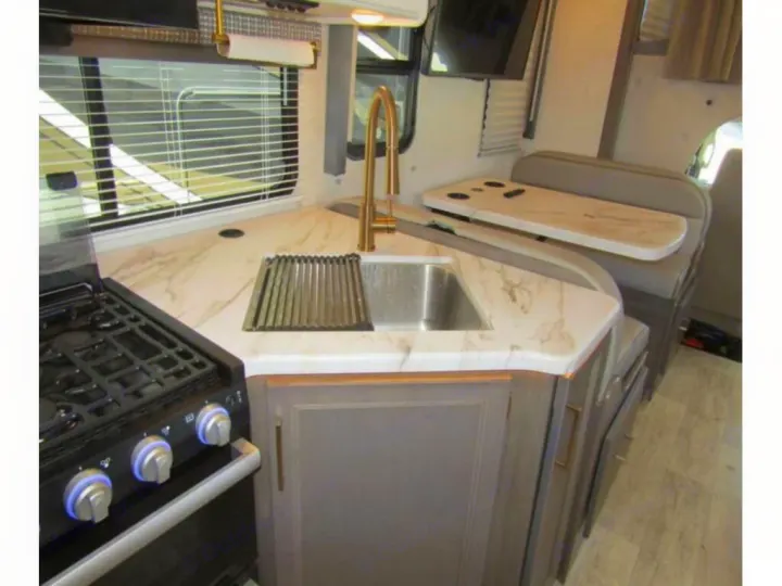 RV rental: Modern kitchen with stove, sink, elegant marble-style counter, and dining booth. Ready for your adventure.. Thor Chateau 2024