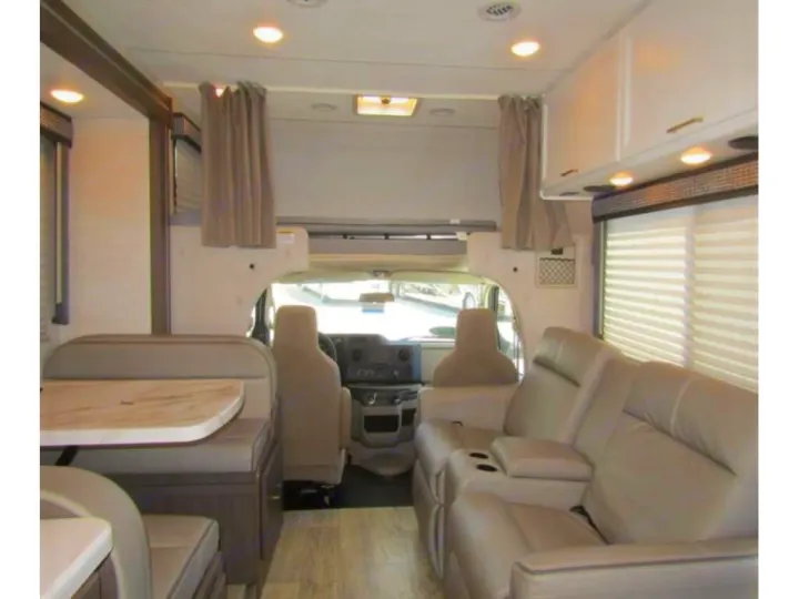Spacious RV rental interior featuring a dining booth, living area with recliners, and front cockpit view.. Thor Chateau 2024