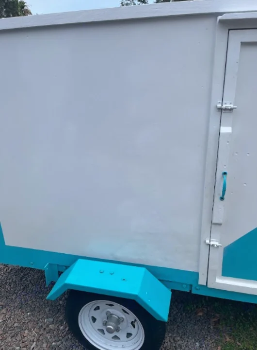 Side view of a white and teal utility trailer with a side door and wheel, a versatile option for RV rental services.. YNGQ Box 2017