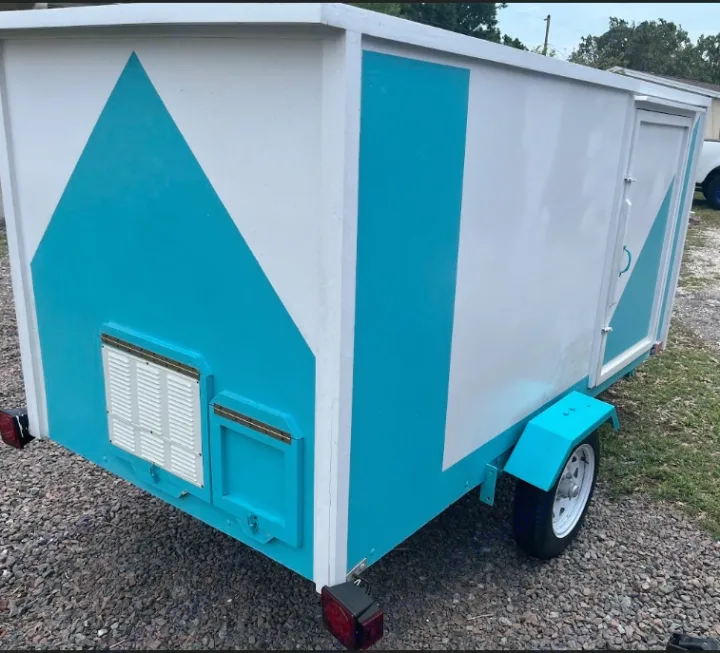 This custom-built teal & white small trailer, resembling a tiny house, ready for an RV rental. Features rear access.. YNGQ Box 2017