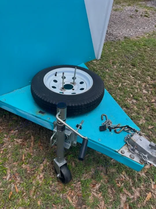 This teal RV rental trailer features a front-mounted spare tire, hitch, and jack, ready for your trip.. YNGQ Box 2017