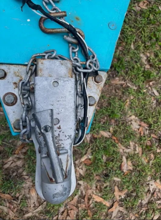 RV rental trailer connection: coupler, safety chains, and wiring on a blue tongue, viewed from above.. YNGQ Box 2017