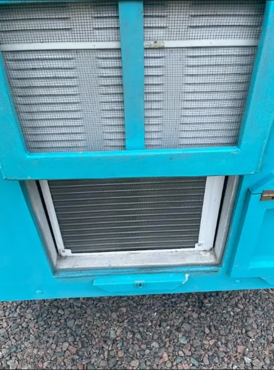 Teal **rv rental** exterior: screened louvered vent and lower cooling fins, parked on gravel.. YNGQ Box 2017