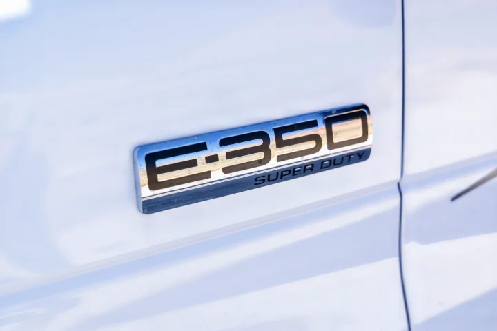 Close-up of a chrome "E-350 Super Duty" badge on a white vehicle, often used for RV rental conversions.. Gulf Stream Conquest 2024