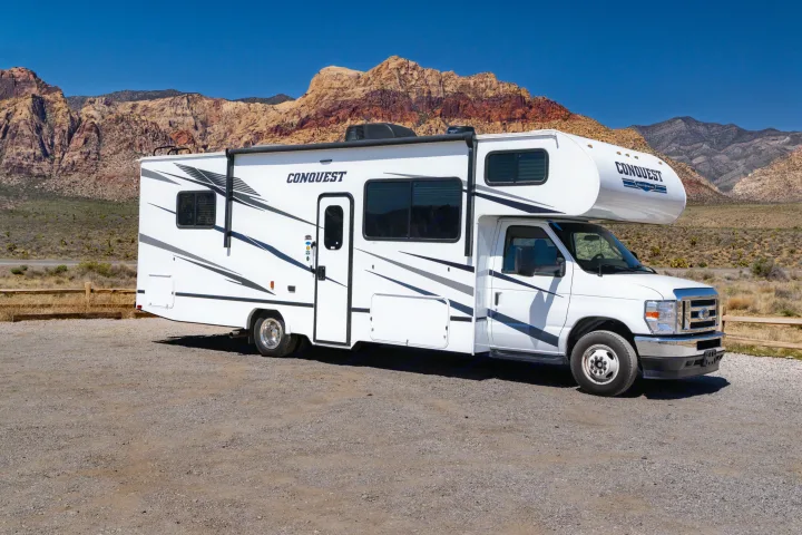 A white Conquest Gulf Stream RV rental parked on a gravel lot, backed by stunning desert mountains under a clear sky.. Gulf Stream Conquest 2024