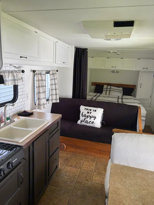 Explore this cozy RV rental interior: modern kitchen with white cabinets, sink, and a comfortable futon & bed area.. Forest River Cherokee Grey Wolf 2012