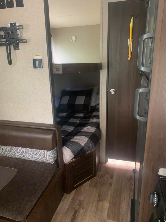 Inside this RV rental: comfortable dinette, cozy bunk beds with plaid bedding, and kitchen space for your trip.. Keystone RV Springdale 2019