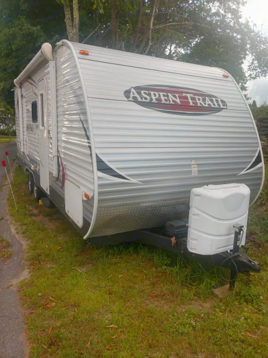 White and gray Aspen Trail travel trailer parked outdoors. An ideal RV rental for your next adventure.. Aspen Trail Aspen Trail Trailer 2013