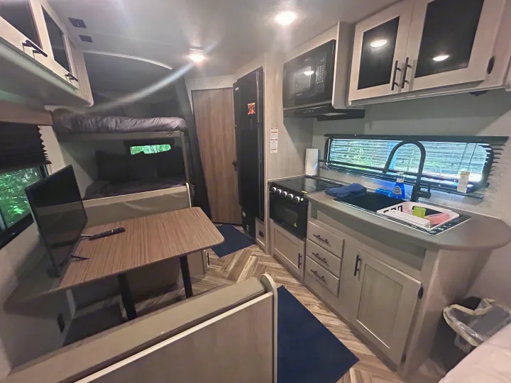 Compact RV rental interior featuring a kitchen, dinette with TV, and bunk beds for comfortable travel.. Crossroads Zinger Lite 2025