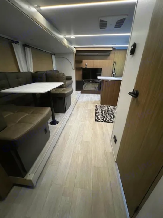 Inside a modern rv rental, featuring a spacious living area with a U-shaped dinette, table, and a well-equipped kitchen.. Forest River 273QBXL 2025