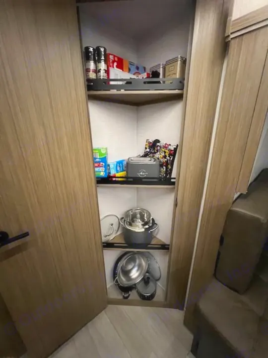 Inside an RV rental: a compact, organized pantry with spices, small appliances, and cookware on corner shelves.. Forest River 273QBXL 2025