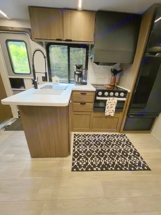 Experience comfort in this modern RV rental kitchen. Features a sink, stove, coffee maker, and wood-look cabinets.. Forest River 273QBXL 2025